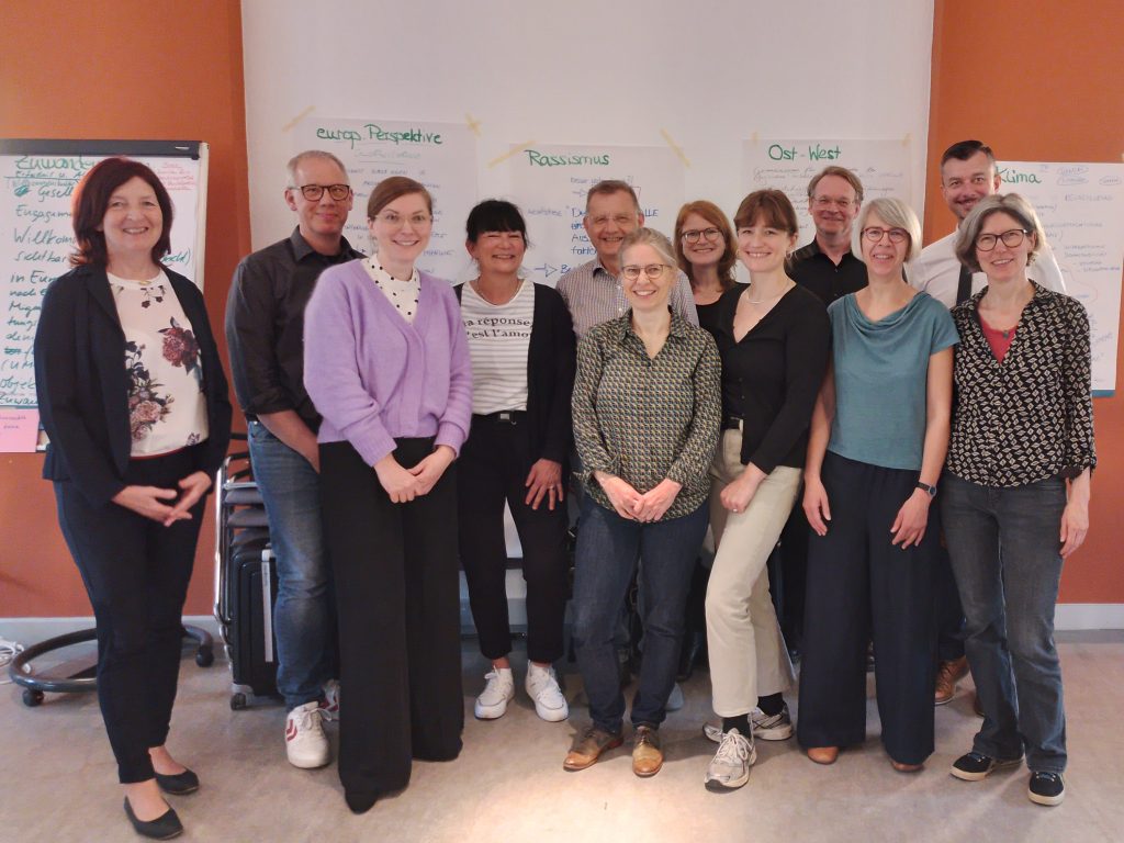 Auf dem Foto sind die Mitglieder der AG Leitpapier zu sehen. Im Hintergrund sieht man beschriftete Flipcharts.